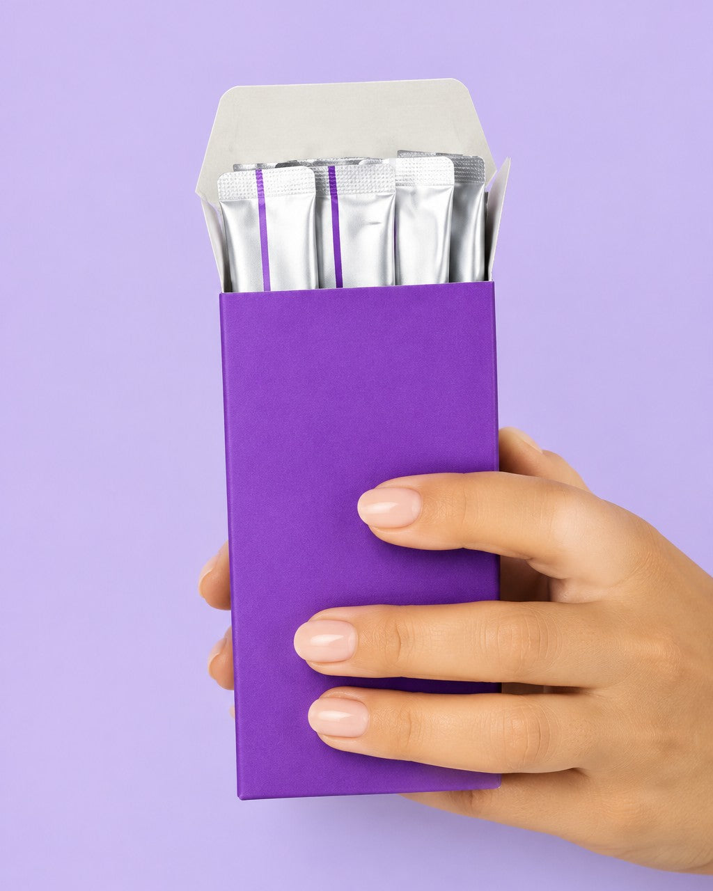 Caja de enjuague blanqueador púrpura con sobres monodosis, en la mano